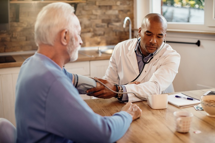 Black general practitioner measuring blood pressure of a senior